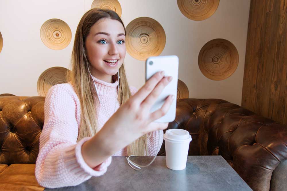 Junge Frau schaut auf ihr Smartphone und lacht dabei